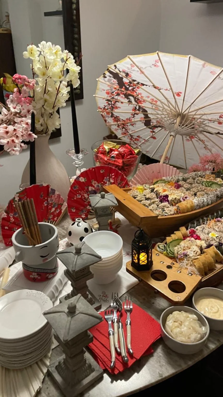 Mesa japonesa con flores, sombrilla y bandejas de sushi